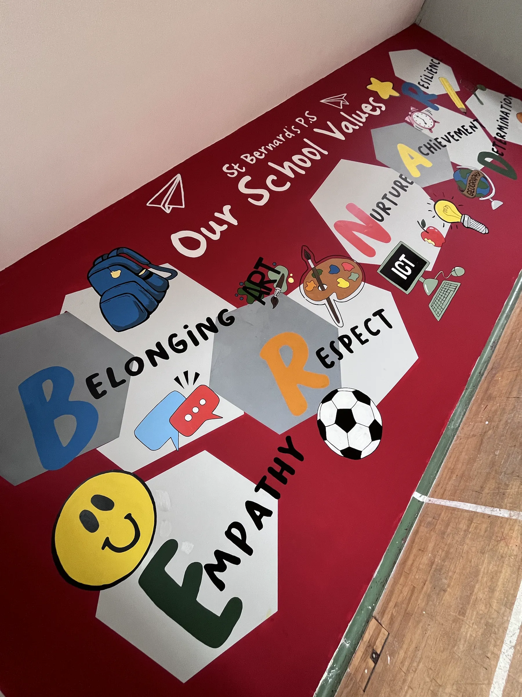 A close-up of the school values wall: Belonging, Respect and Empathy on white hexagons with a smiley face and a football.