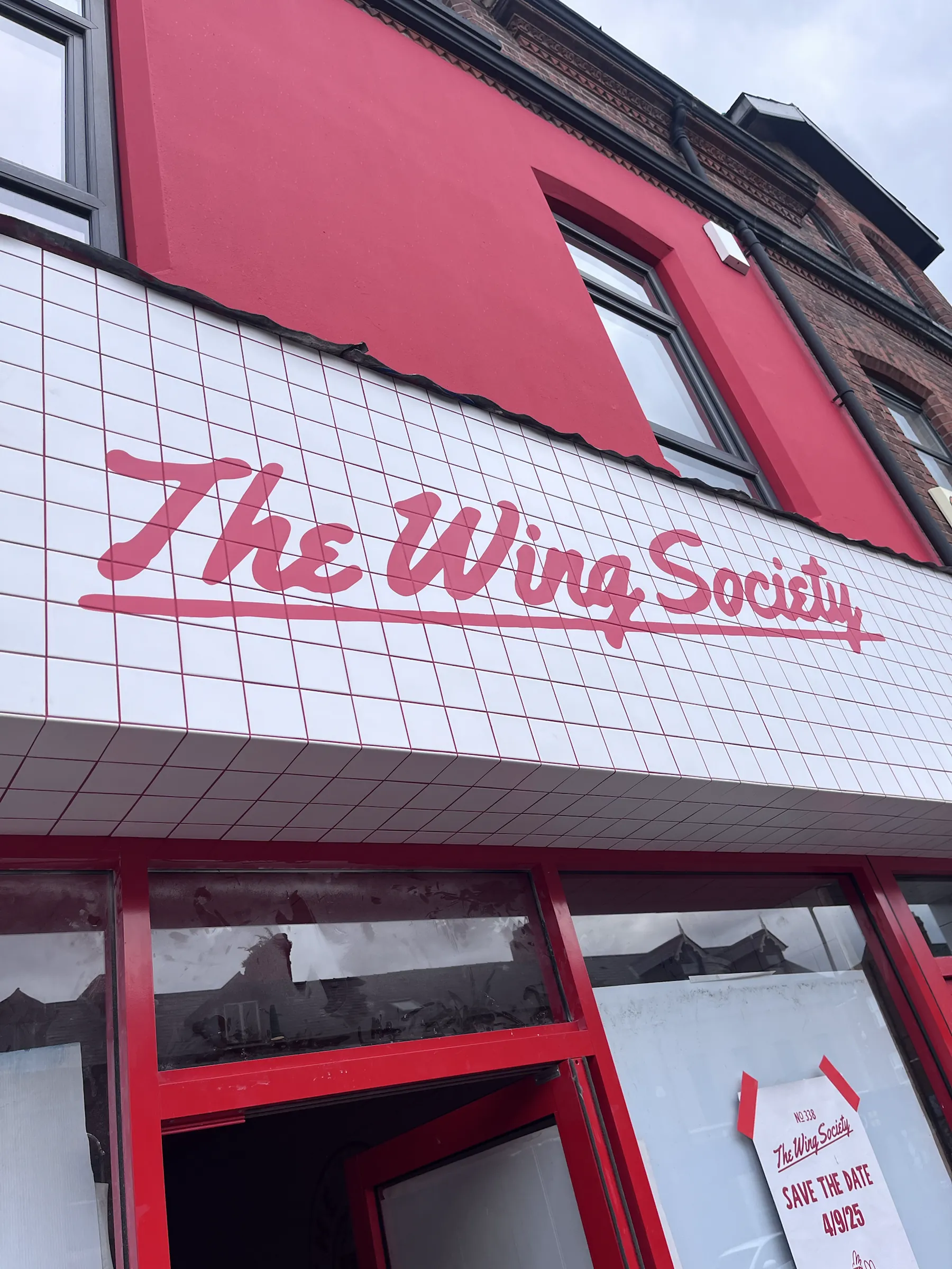 “The Wing Society” in red script painted across the white-tiled fascia above the shopfront.